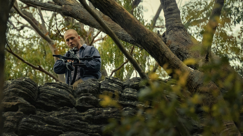 Ben holding a crossbow in the woods in Apex