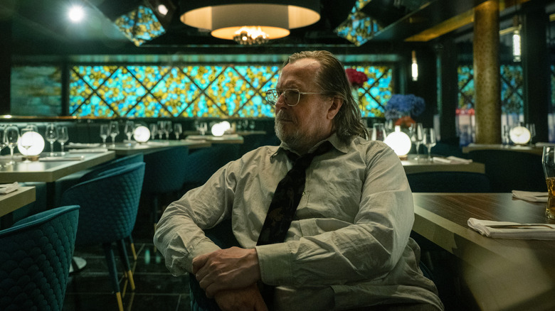 Gary Oldman's Jackson Lamb looks off into the distance as he sits in a restuarant in Slow Horses
