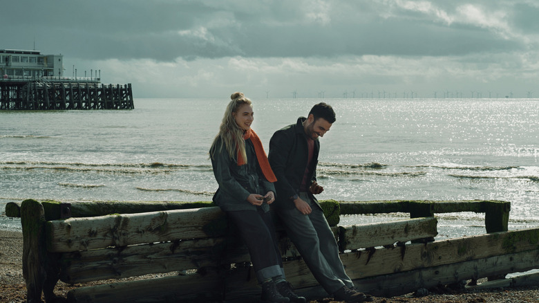 Imogen Poots as Laura and Brett Goldstein as Simon sitting by a pier and laughing in All of You