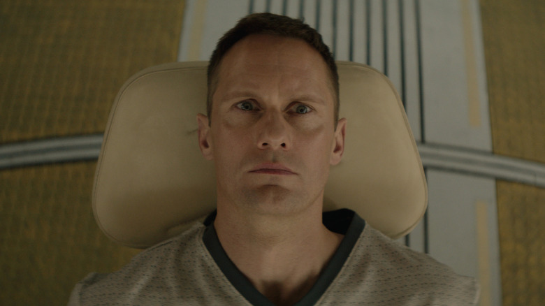 Alexander Skarsgård as Murderbot lying back on a medical chair on Murderbot