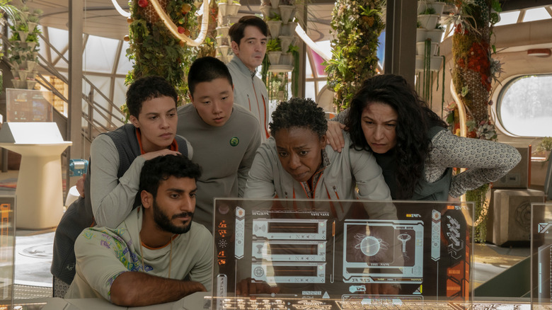 Akshay Khanna als Ratthi, Tattiawna Jones als Arada, Sabrina Wu als Pin-Lee, David Dastmalchian als Gurathin, Noma Dumezweni als Ayda Mensah en Tamara Podemski als Bharadwaj kijkend naar een computerscherm op Murderbot
