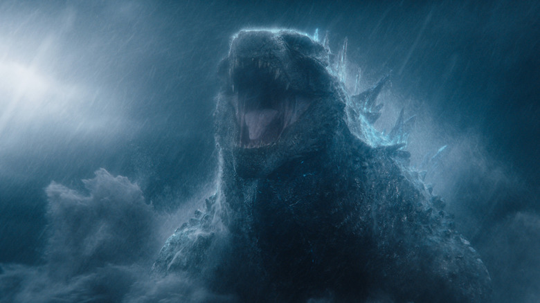 Godzilla in the role of Godzilla standing in a rainstorm at night and roaring in Monarch: Legacy of Monsters season 2