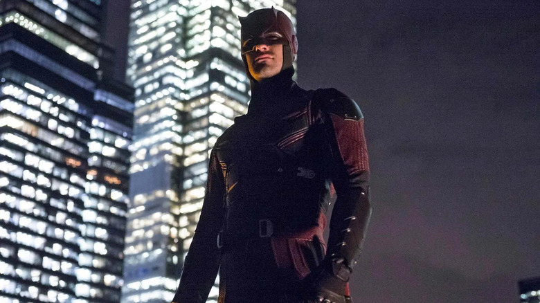 man in dark red superhero suit standing on an nyc rooftop