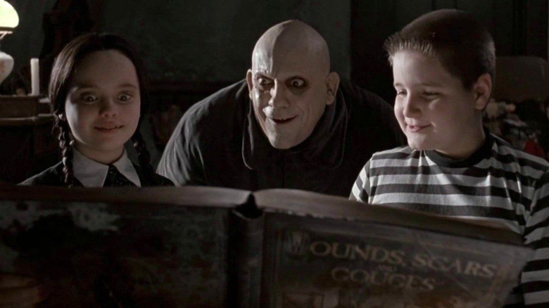 Wednesday, Fester, and Pugsley read a book in The Addams Family movie