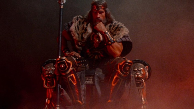 Arnold Schwarzenegger as Conan sitting on his throne at the end of Conan the Barbarian