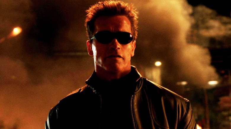 Arnold Schwarzenegger's Terminator stands in a smokey street at night in Terminato 3 Rise of the Machines