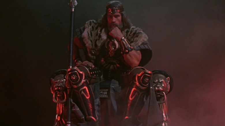 Arnold Schwarzenegger as King Conan sitting on his throne at the end of Conan the Barbarian