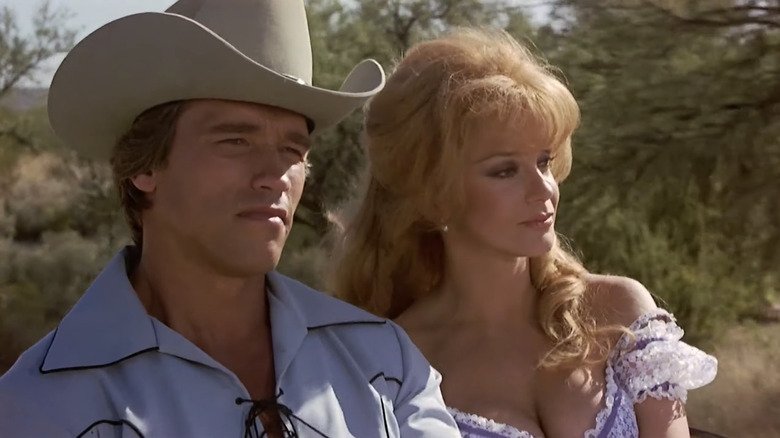 அழகான அந்நியனாக அர்னால்ட் ஸ்வார்ஸ்னேக்கர் தி வில்லனில் ஆன்-மார்க்ரெட் சார்மிங் ஜோன்ஸாக அமர்ந்திருக்கிறார்