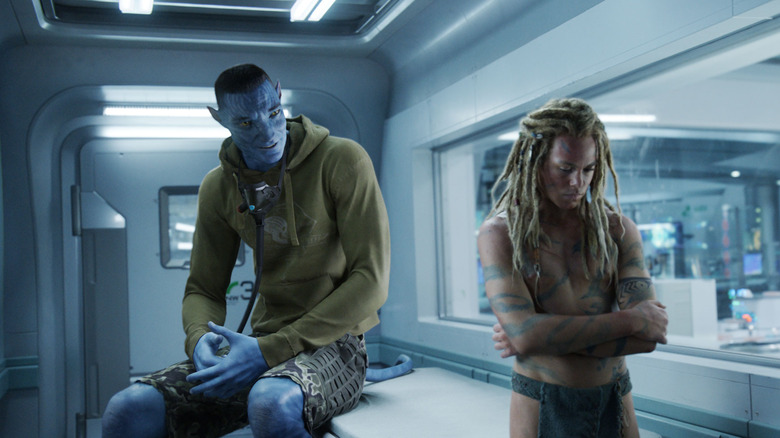 Stephen Lang as Colonel Miles Quaritch sitting on a table next to Jack Champion as Spider in a lab room in Avatar: Fire & Ash