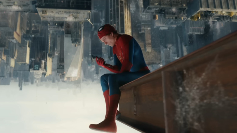 Tom Holland as Peter Parker sitting upside down on a steel girder overlooking New York City and staring at his phone in Spider-Man: Brand New Day