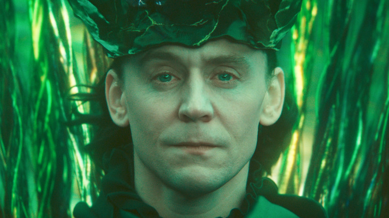 Tom Hiddleston as Loki wearing a crown and surrounded by green filaments in Loki