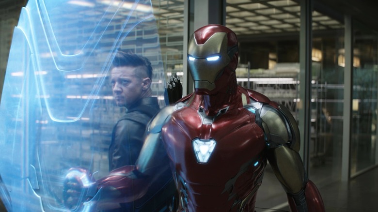 Robert Downey, Jr. as Tony Stark wearing his Iron Man armor standing in a warehouse next to Jeremy Renner as Clint Barton in Avengers: Endgame