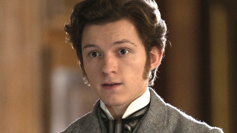 Tom Holland as Samuel Insull smirking with his arms folded in front of him in The Current War