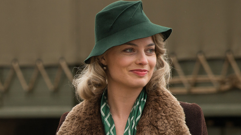 woman in a green brimmed hat and a fur coat on smiling off to her left