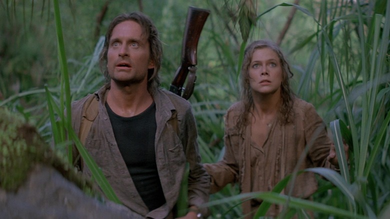 Michael Douglas as Jack and Kathleen Turner as Joan standing in the jungle in Romancing the Stone