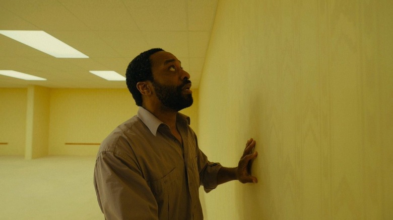 Chiwetel Ejiofor as Clark touching a yellow wall in Backrooms