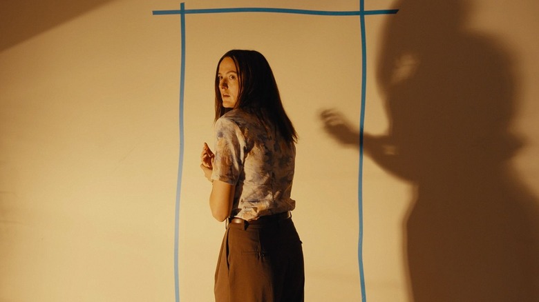 Renate Reinsve as Mary walking up to a wall and looking over her shoulder in Backrooms