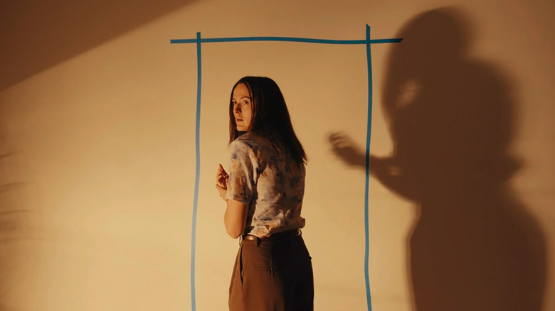 Dr. Mary Kline casts a shadow on a wall with a tape door outline in Backrooms