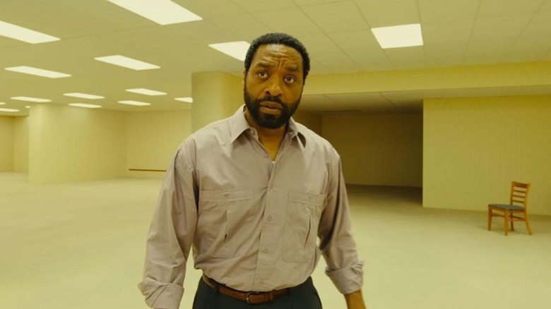 Chiwetel Ejiofor as Clark in a mostly empty yellow room with just a chair in Backrooms