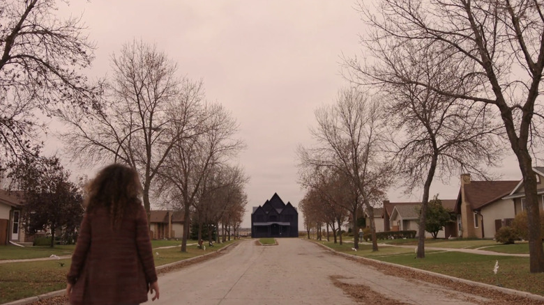 Jess Salgueiro's Lacy Evans walks towards a black house in a suburban street in Channel Zero