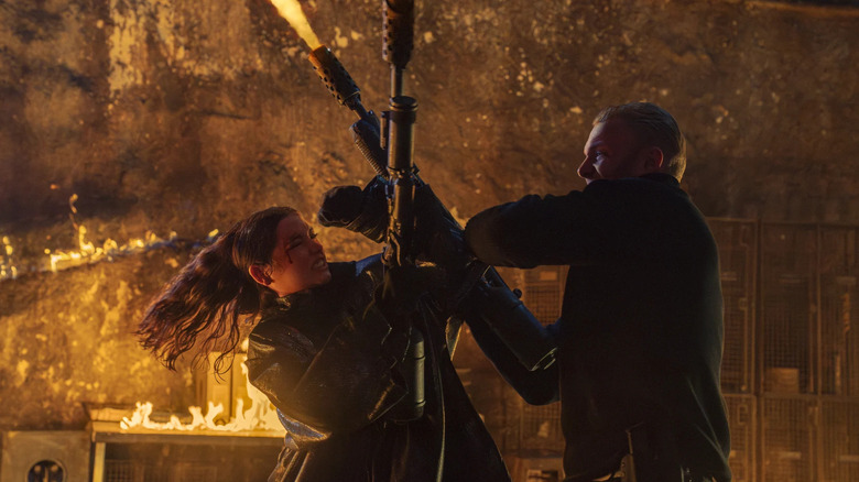 Eve, holding a flamethrower, fights a guy holding another flamethrower in Ballerina