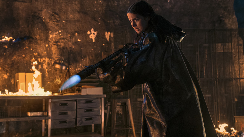 Ana de Armas as Eve Macarro brandishing a flamethrower and wearing a fire-resistant coat in Ballerina