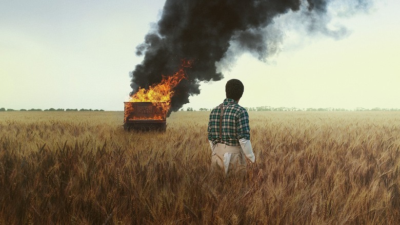 John David Washington como Boy Willie observa um piano queimar em um campo de trigo em The Piano Lesson