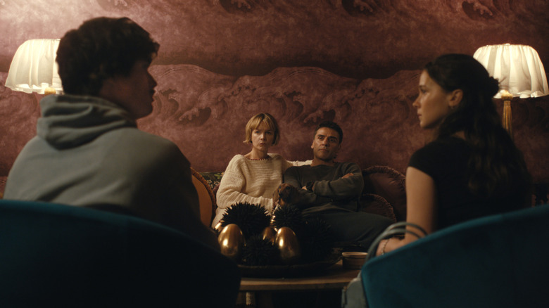Oscar Isaac as Josh Martín and Carey Mulligan as Lindsay Crane-Martín sitting on a chair opposite Charles Melton as Austin Davis and Cailee Spaeny as Ashley Miller in Beef