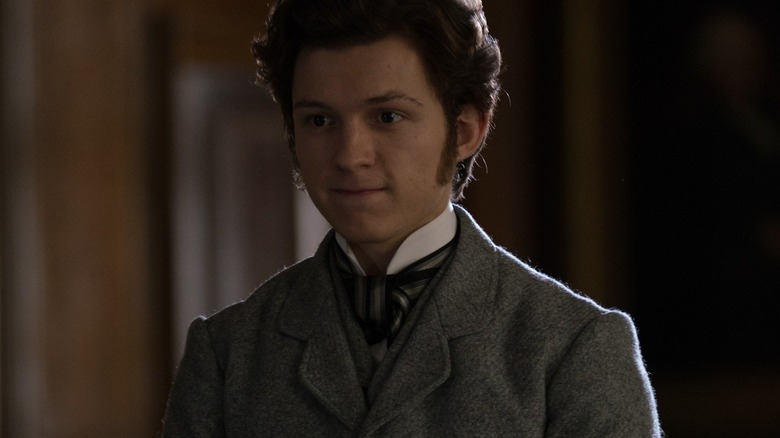 Tom Holland as Samuel Insull smirking with his arms folded in front of him in The Current War