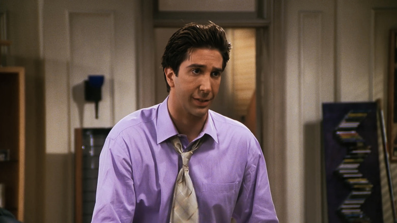 David Schwimmer as Ross Gellar stands in Chandler and Joey's apartment wearing a shirt and tie in Friends