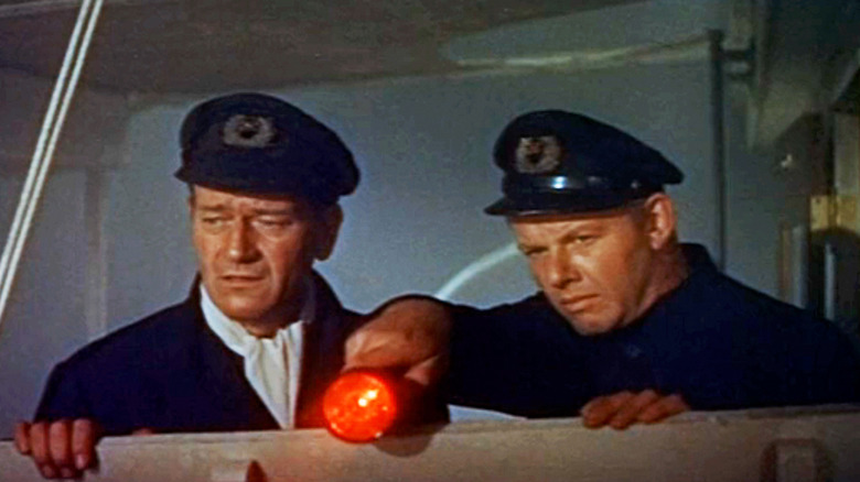 John Wayne's Captain Karl Ehrlich stands alongside Alan Hale Jr's Wentz as he shines a flashlight in The Sea Chase