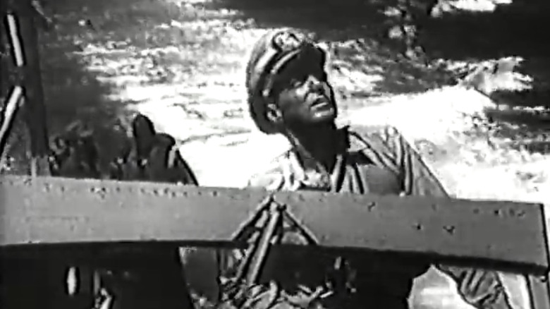 John Baer's John F Kennedy stands at the helm of a boat in Navy Log