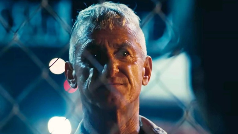 Sean Penn as Colonel Lockjaw staring through a fence in One Battle After Another