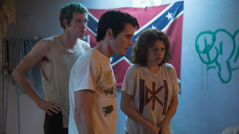 Callum Turner as Tiger, Anton Yelchin as Pat, and Alia Shawkat as Sam staring at a door in Green Room