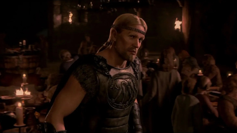 Beowulf in the great hall with people behind him in Beowulf.