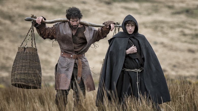 Jon Bernthal as The Mute and Tom Holland as Brother Diarmuid wander through a field in Pilgrimage