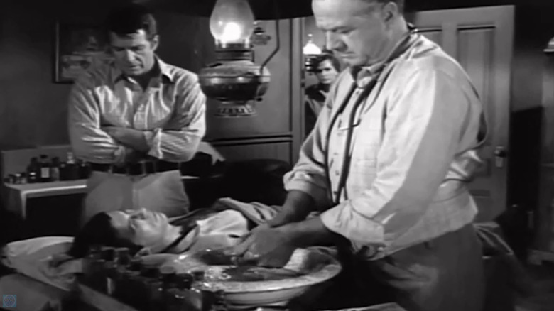 Leonard Nimoy's Del Hillman lays on a table as James Seay's Doctor prepares to treat him with Robert Horton's Shenandoah watching in A Man Called Shenandoah