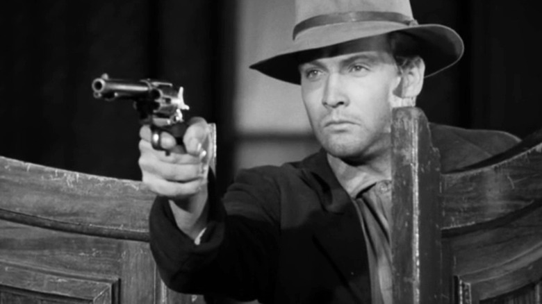Lee Majors' Dave Lukens aims a pistol through saloon doors in Gunsmoke