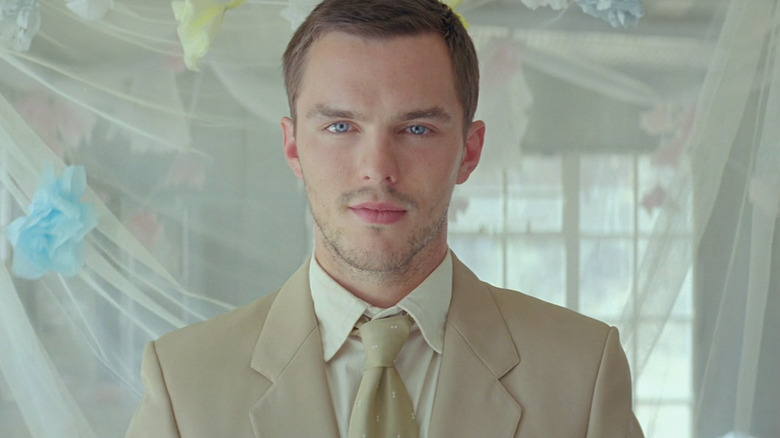 Nicholas Hoult's Flem Lever smiles as he stands in a suit in Young Ones