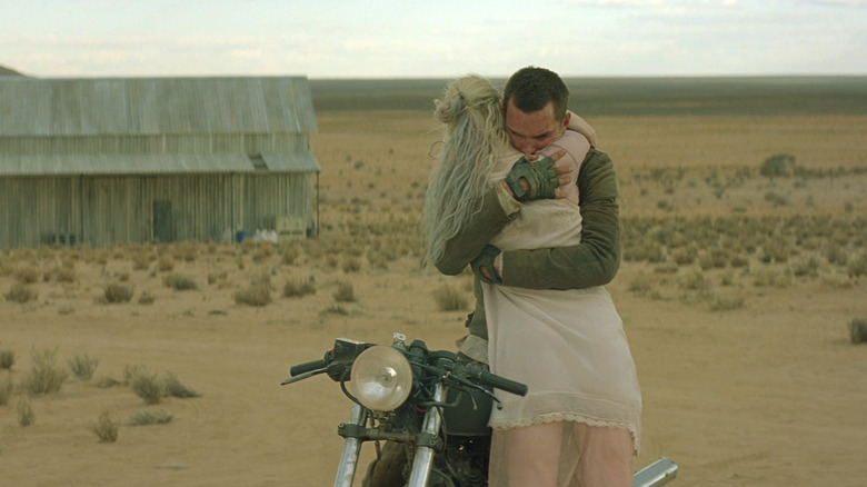 Nicholas Hoult's Flem Lever sits on a motorcycle and hugs Elle Fanning's Mary Holm in the desert in Young Ones