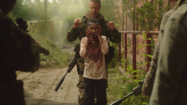 The Girl with All The Gifts - Melanie standing in front of Sergeant Eddie Parks in overgrown abandoned city landscape