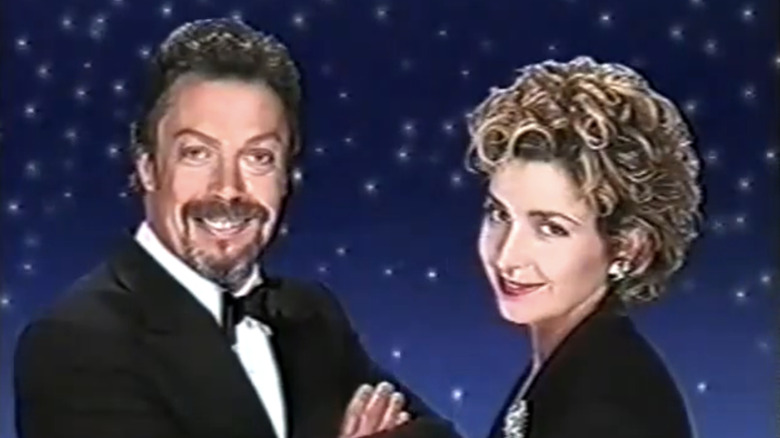 Tim Curry's Simon Ferguson and Annie Potts' Hadley Martin stane side by side in the opening titles for Over the Top