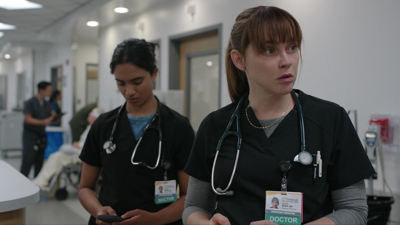 Supriya Ganesh as Dr. Samira Mohan standing behind Fiona Dourif's Dr. Cassie McKay in The Pitt