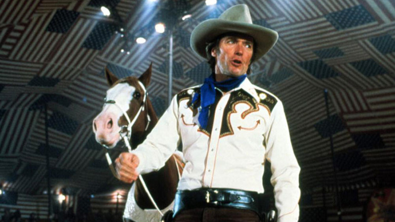 Bronco Billy (Clint Eastwood) leads a horse by the reins under a big top tent in Bronco Billy