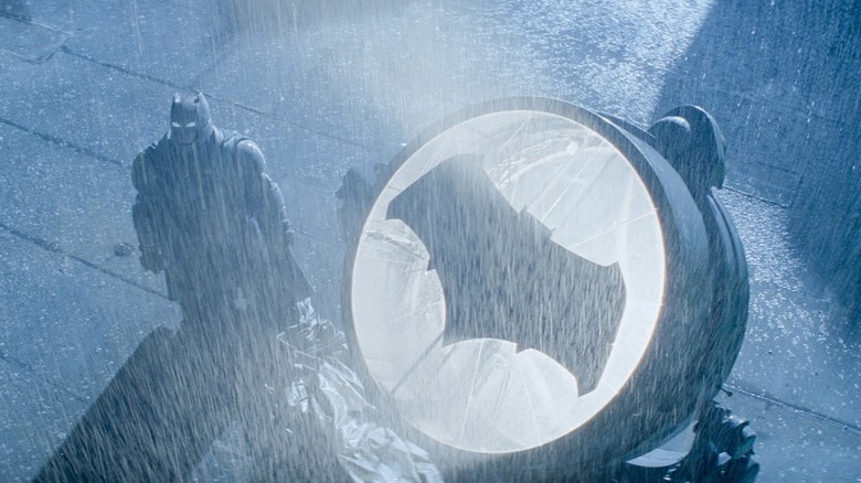 Batman v. Superman - Batman standing in rain next to Batsignal