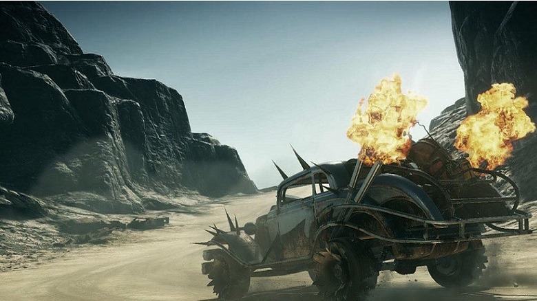 A spiky Mad Max car drives through a canyon