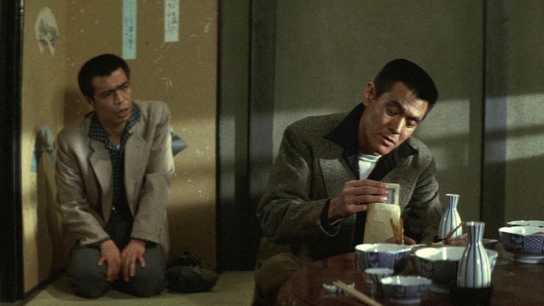 A man watches Shozo Hirono (Bunta Sugawara) count movie in an envelope in Battles Without Honor and Humanity