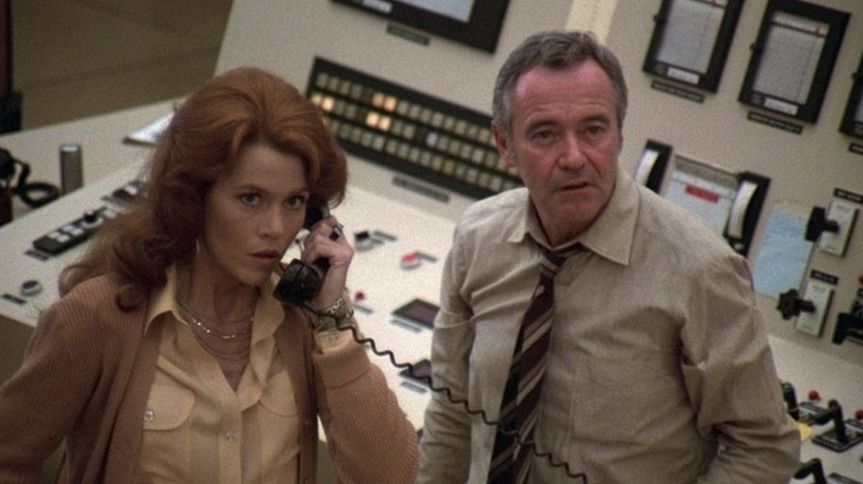 Kimberly Wells (Jane Fonda) speaks on a phone standing next to Jack Godell (Jack Lemmon) in The China Syndrome