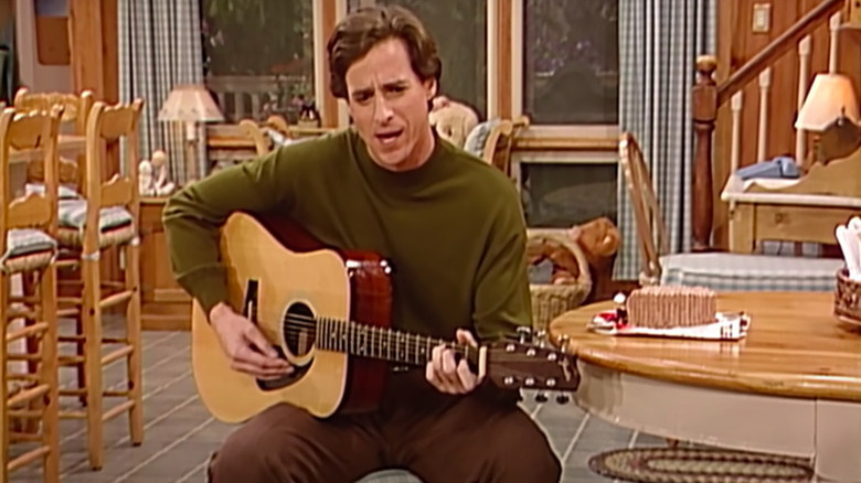 Danny Tanner (Bob Saget) plays guitar in his dining room in Full House