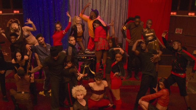 The cast of Climax in various dance poses in front of curtains forming a French flag